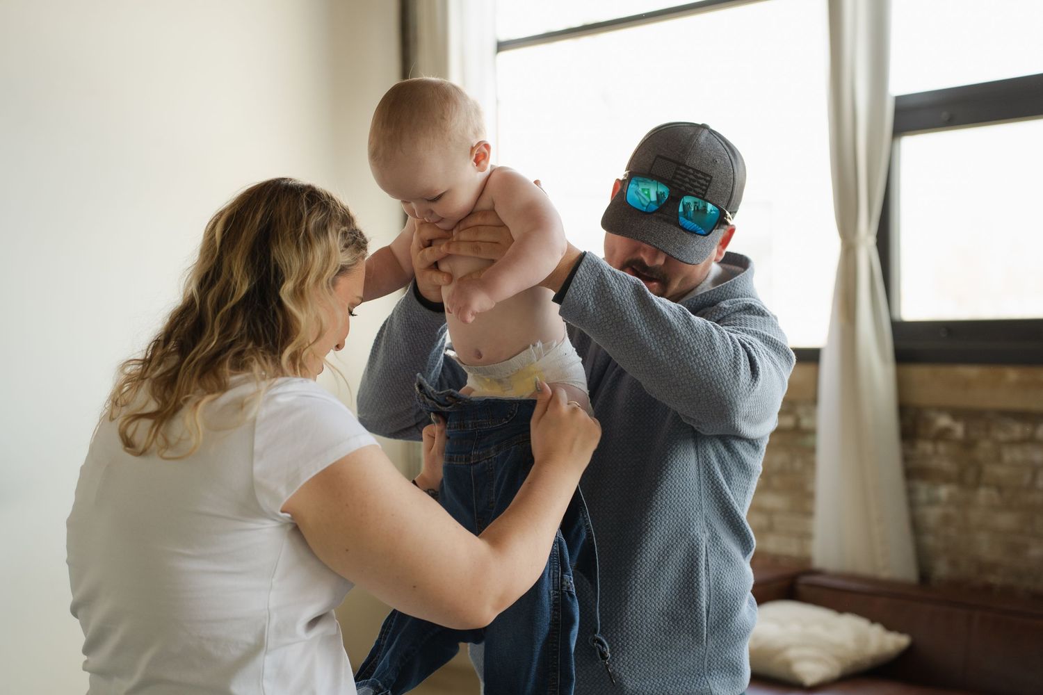 A family shares a playful moment together in a bright room with natural light streaming through the window.
