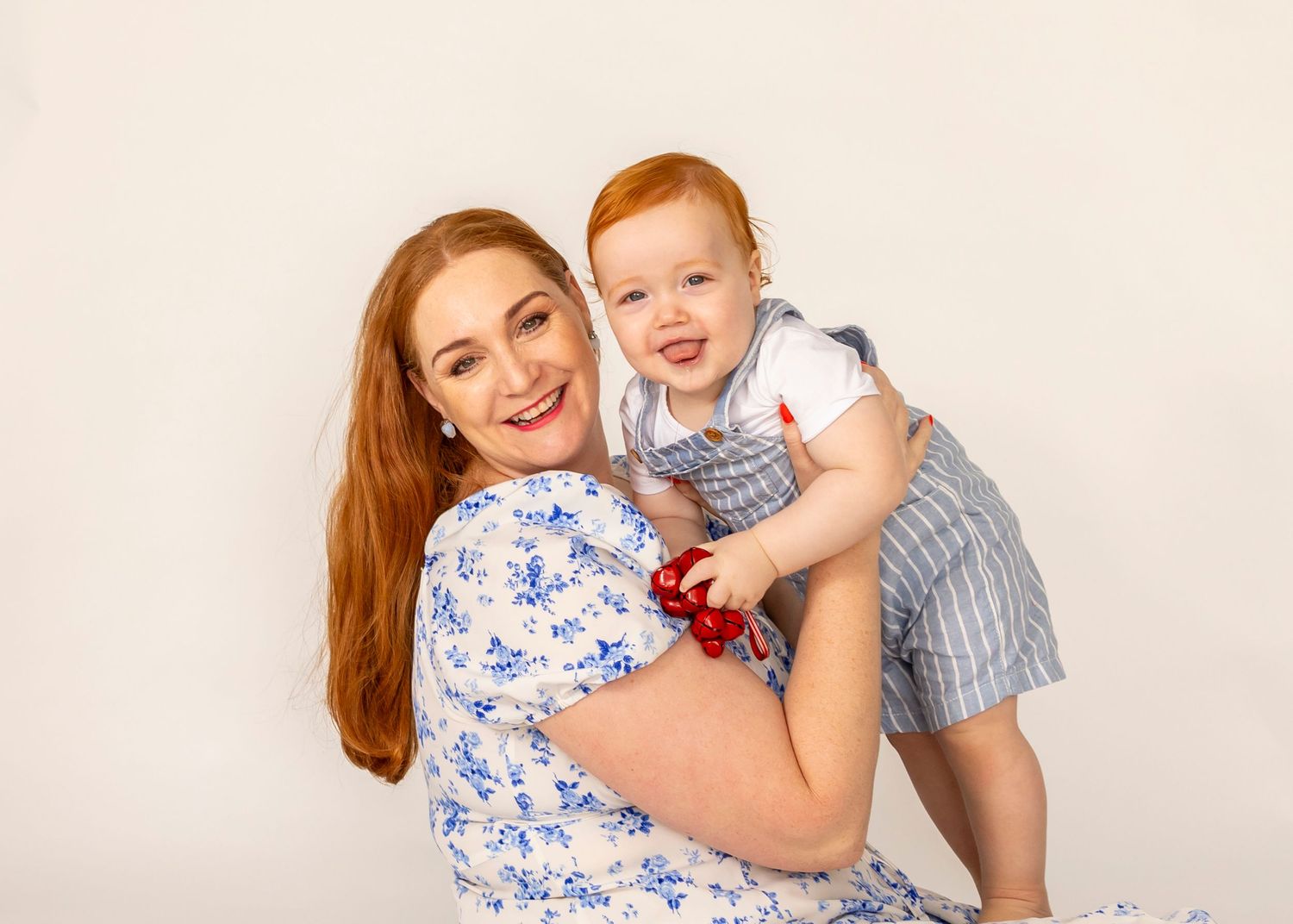 Natural studio moment of mum and son laughing together against a white background