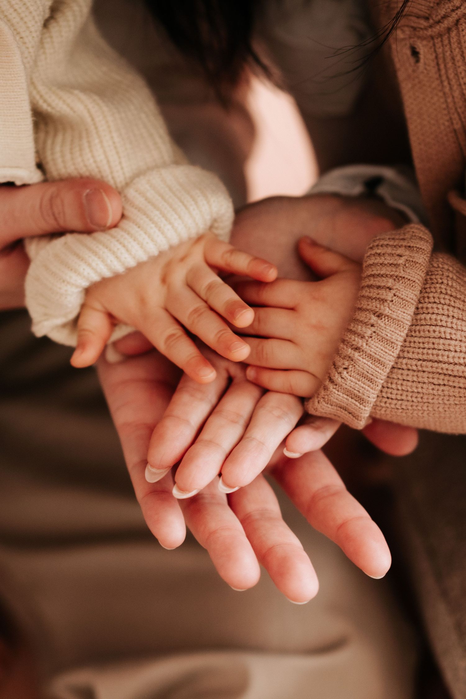 Two hands gently clasped together in a tender moment wearing knit sweaters against a warm brown background.兩隻穿著針織毛衣的手在溫暖的棕色背景下輕輕交握，畫面溫馨動人。