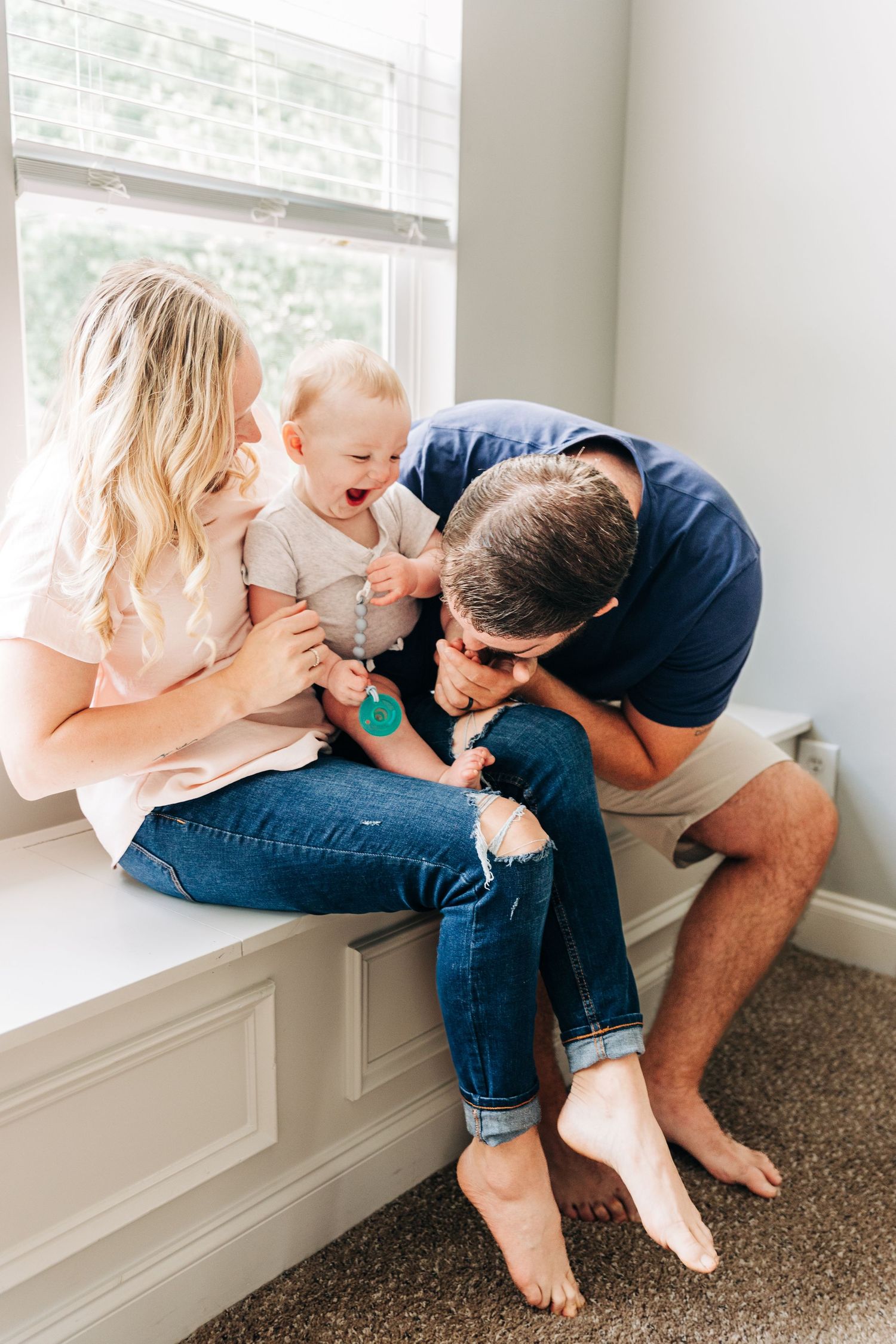 A tender family moment captured in a series of photos showing parents bonding with their newborn baby near a window.
