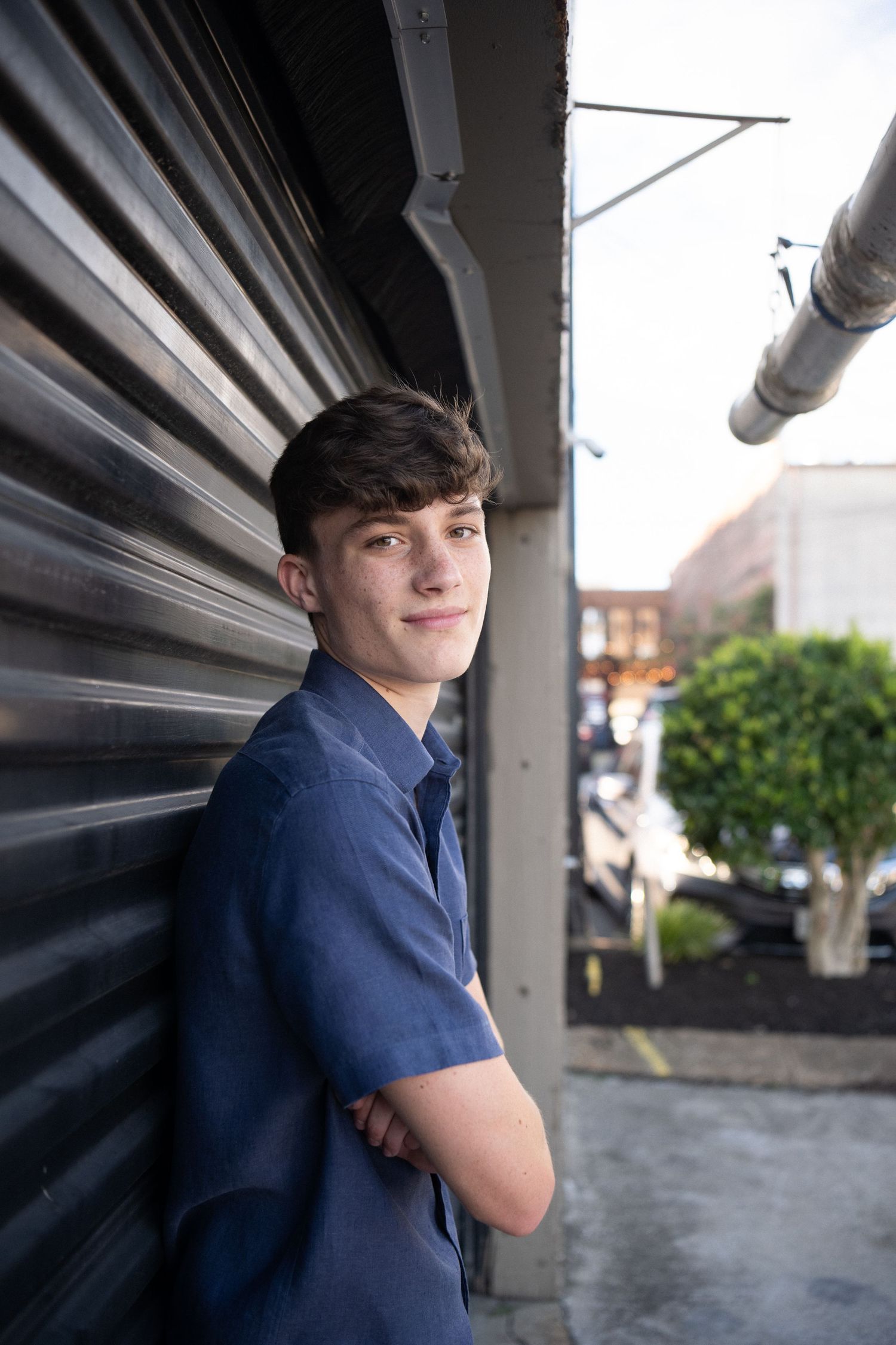 Person in navy blue shirt leans against a wall in an outdoor urban setting with multiple similar poses shown.