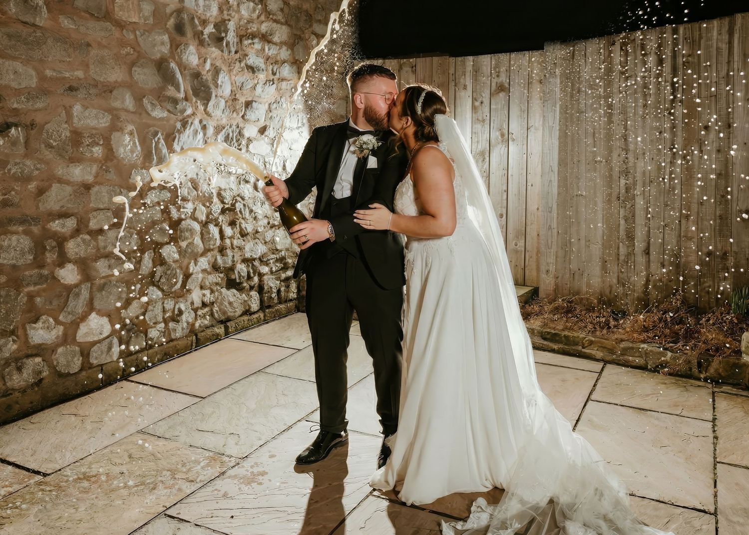 A couple shares an intimate dance moment during their wedding celebration against a rustic stone wall backdrop at the coniston hotel