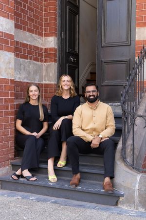 team photo, sitting on stone steps in front of a brick building Fremantle High St