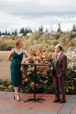 A couple shares an intimate moment outdoors on a brick patio with autumn flowers and greenery in the background.