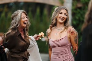 Group of friends in mauve and brown dresses laughing together outdoors during a photo session.