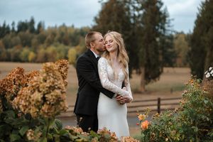 Romantic autumn wedding photos taken in front of evergreen trees and fall foliage.