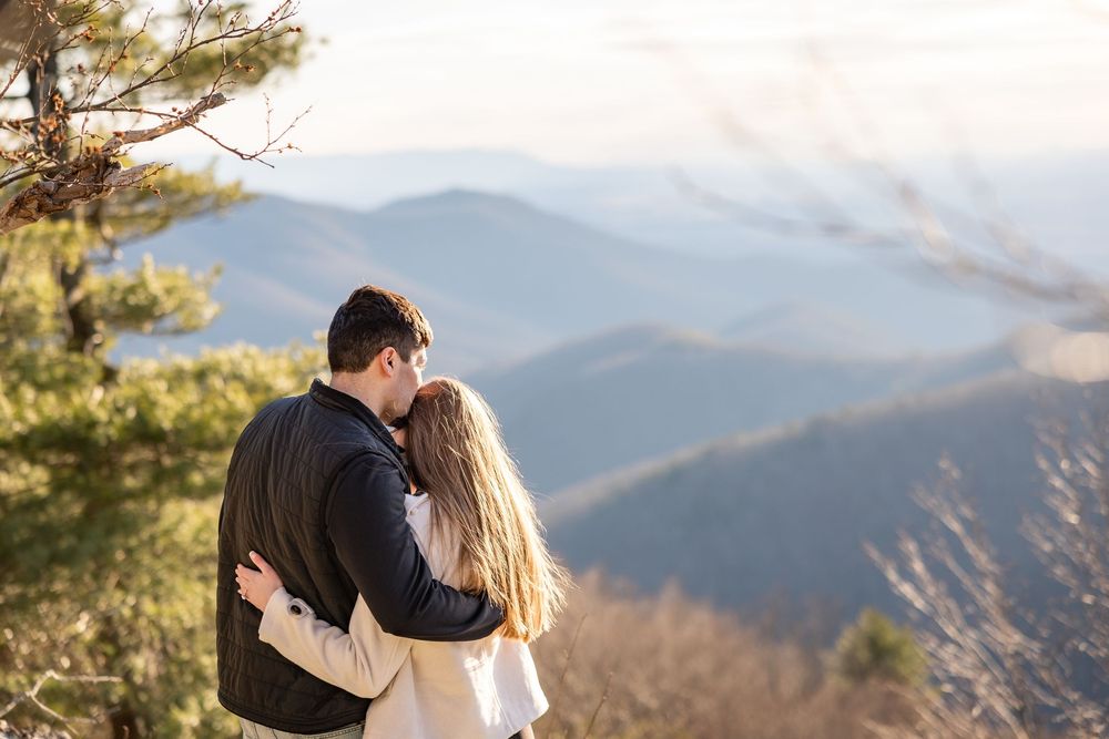 A couple embraces while enjoying a scenic mountain vista during sunset in the Blue Ridge Mountains.