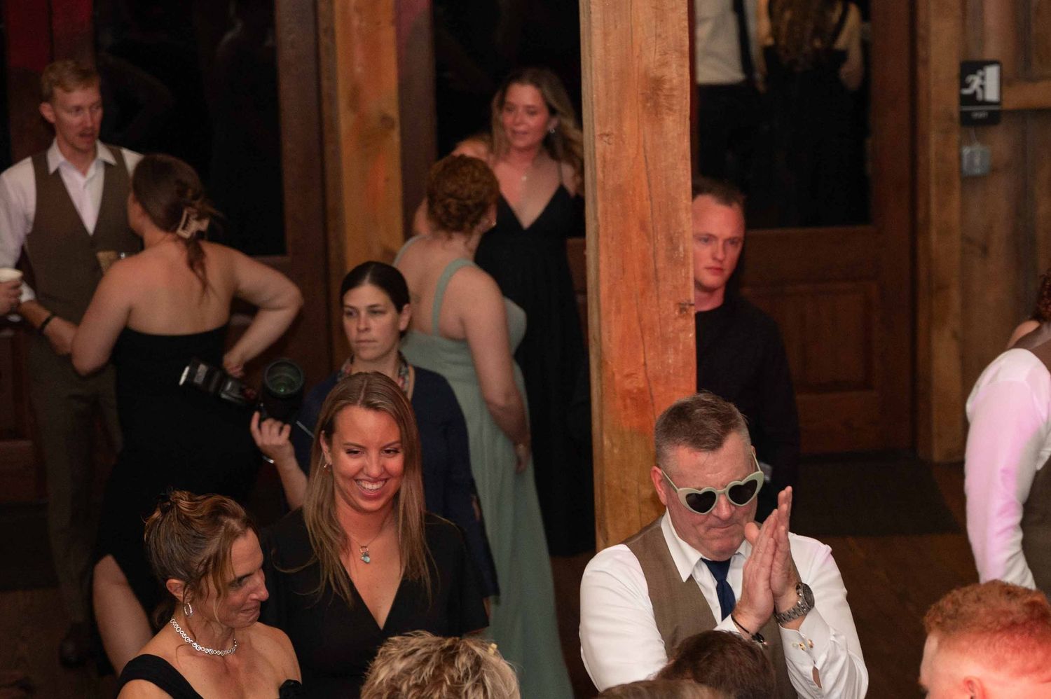 People gathered at a rustic indoor venue with wooden pillars during what appears to be a social event or celebration.