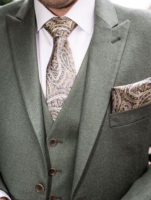 A stylish olive green three-piece suit with a coordinating paisley tie and pocket square showing fine tailoring details.