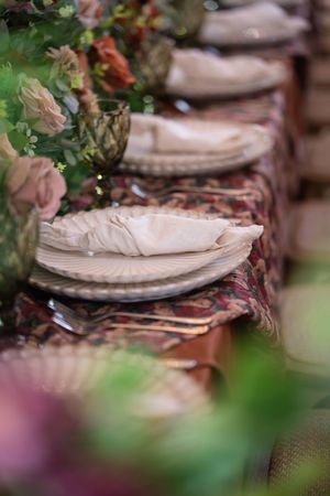 Elegant table settings with vintage plates and floral decorations arranged in a repeating pattern for a formal dining event.