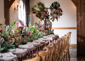 Rustic wooden banquet tables decorated with floral arrangements and place settings in an elegant reception venue.