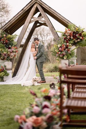 A rustic outdoor wedding ceremony setup with wooden benches and beautiful floral arrangements in warm autumn colors.