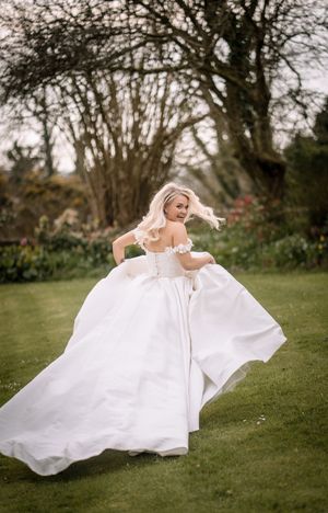 A bride in a flowing white wedding dress twirls gracefully on a grassy lawn in a series of dynamic motion shots.