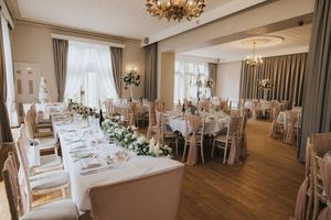 Elegant white wedding reception venue with crystal chandeliers, floral centrepieces and wooden floors in natural light at Cave Castle.