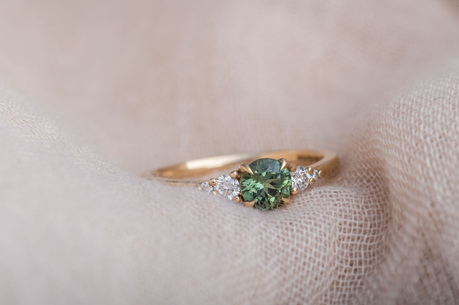 Vintage-inspired ring with aqua gemstone and diamond accents on textured fabric.