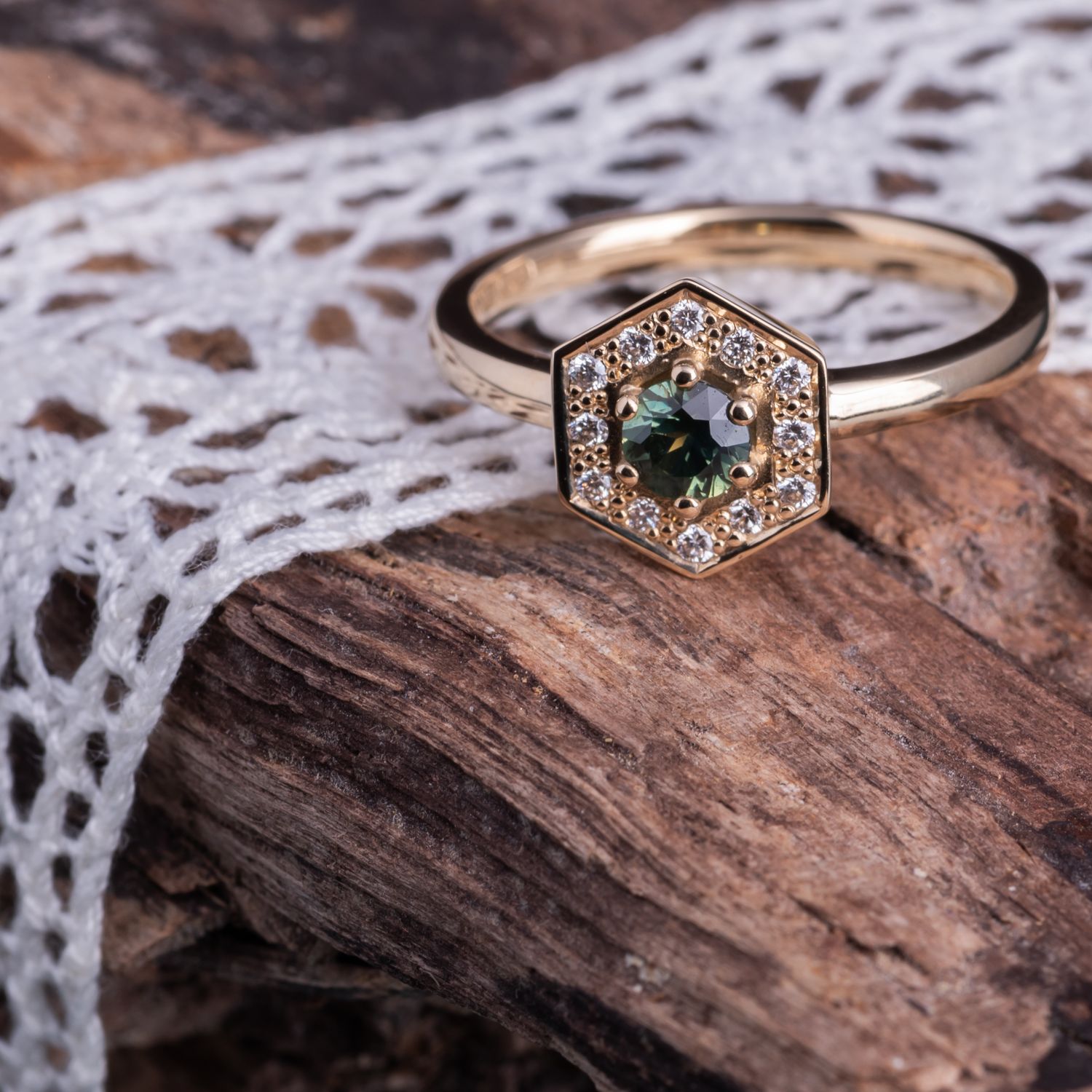 Collection of geometric rings with teal stones and diamonds displayed on rustic wood and lace.