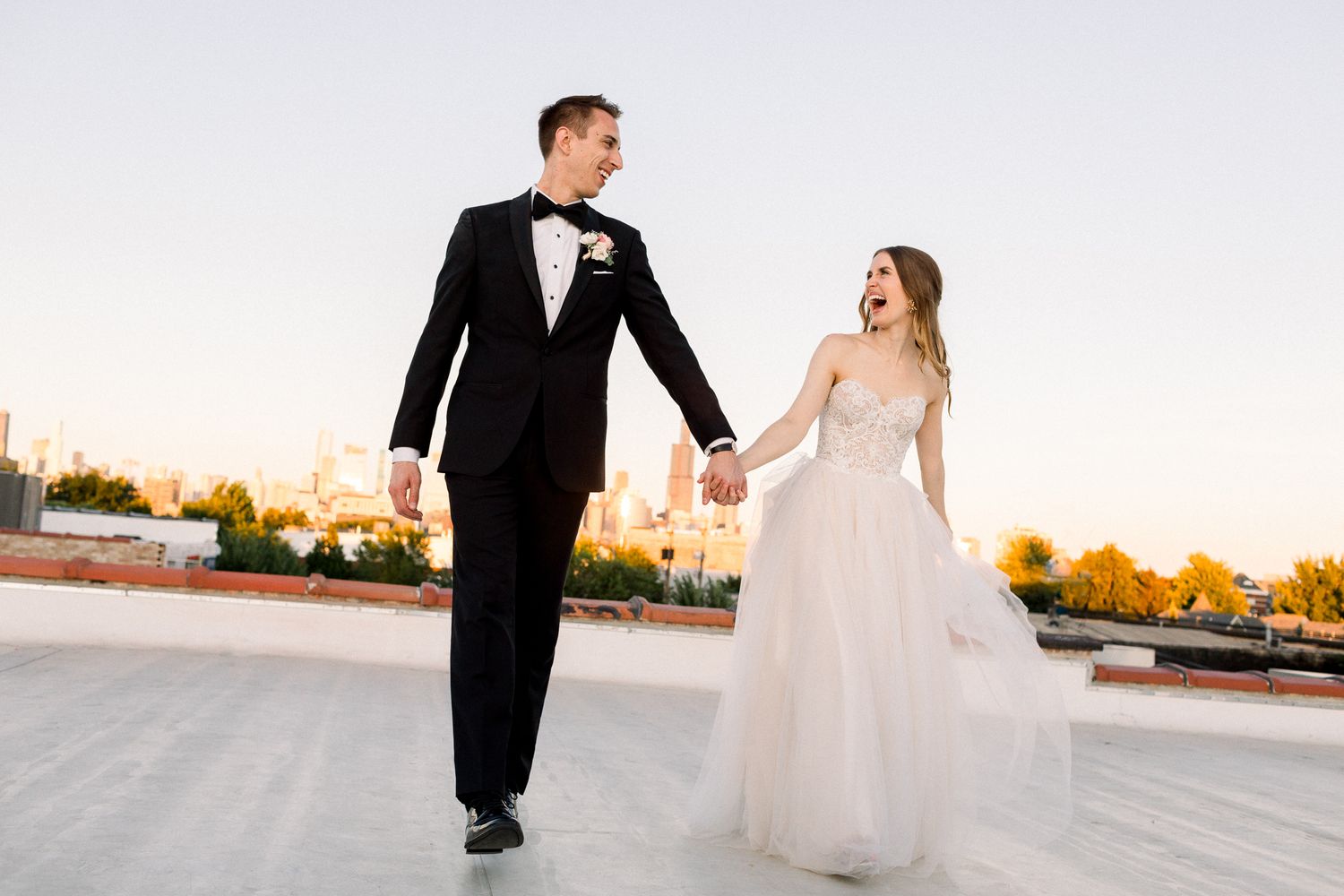 Newlyweds celebrate during wedding ceremony as guests shower them with white flower petals in outdoor garden setting.
