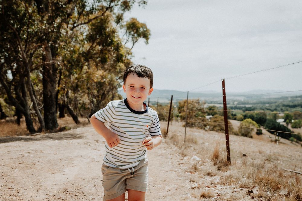 A person in striped shirt poses with hands on hips on a dirt trail overlooking hills.
Altona Family Photographer Melbourne