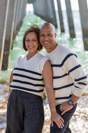 Couple in coordinating striped outfits smile together in outdoor setting.