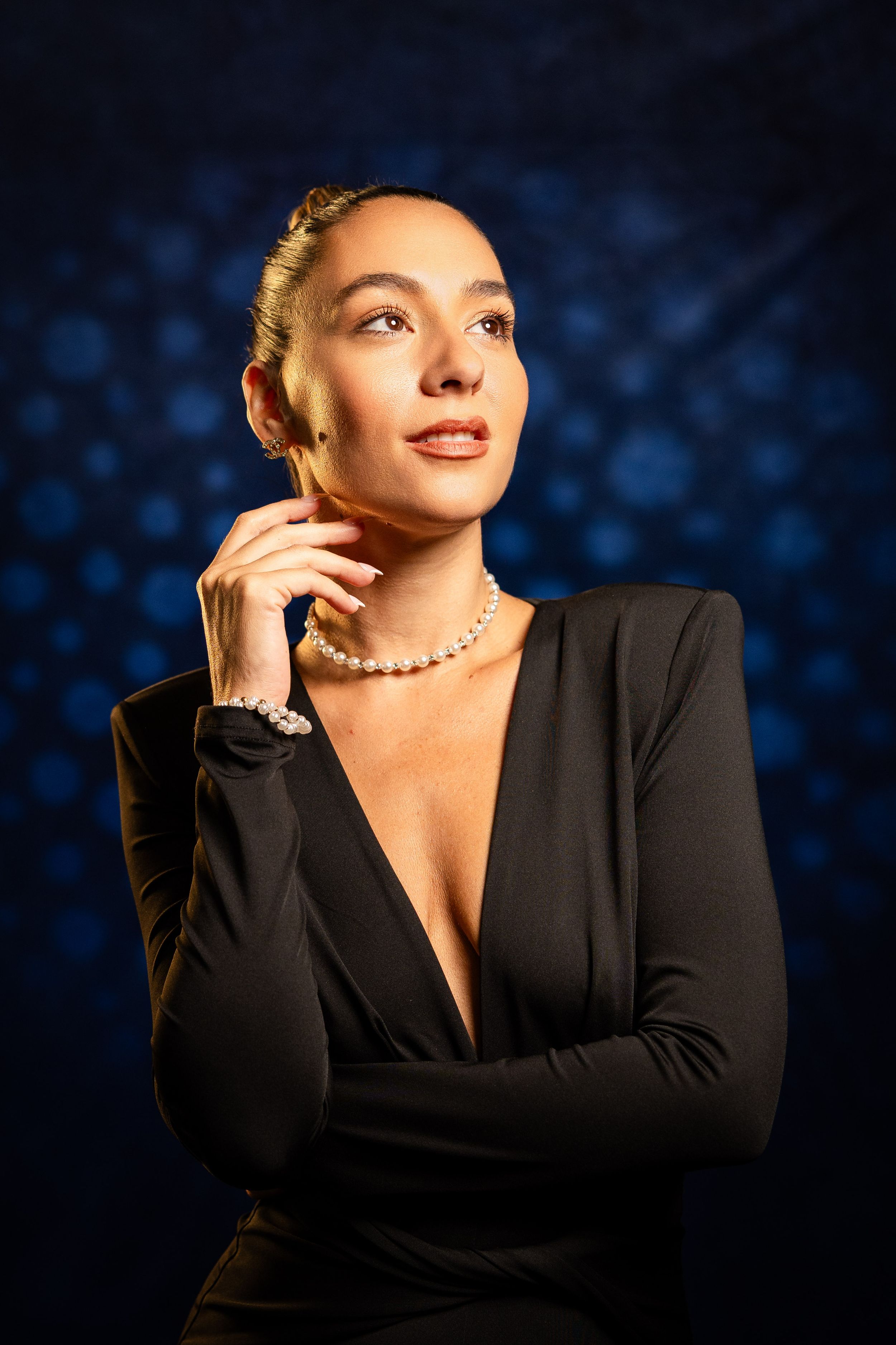 Studio portrait series with model in black blazer against blue bokeh background.