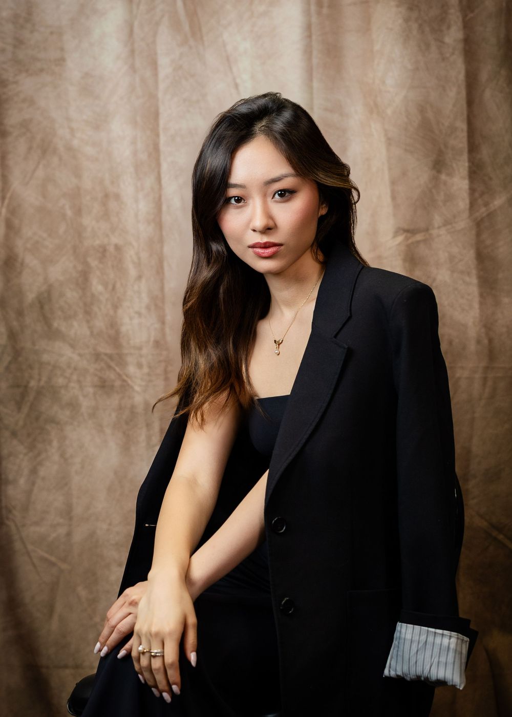 Fashion portrait series of model in black blazer against textured brown backdrop.