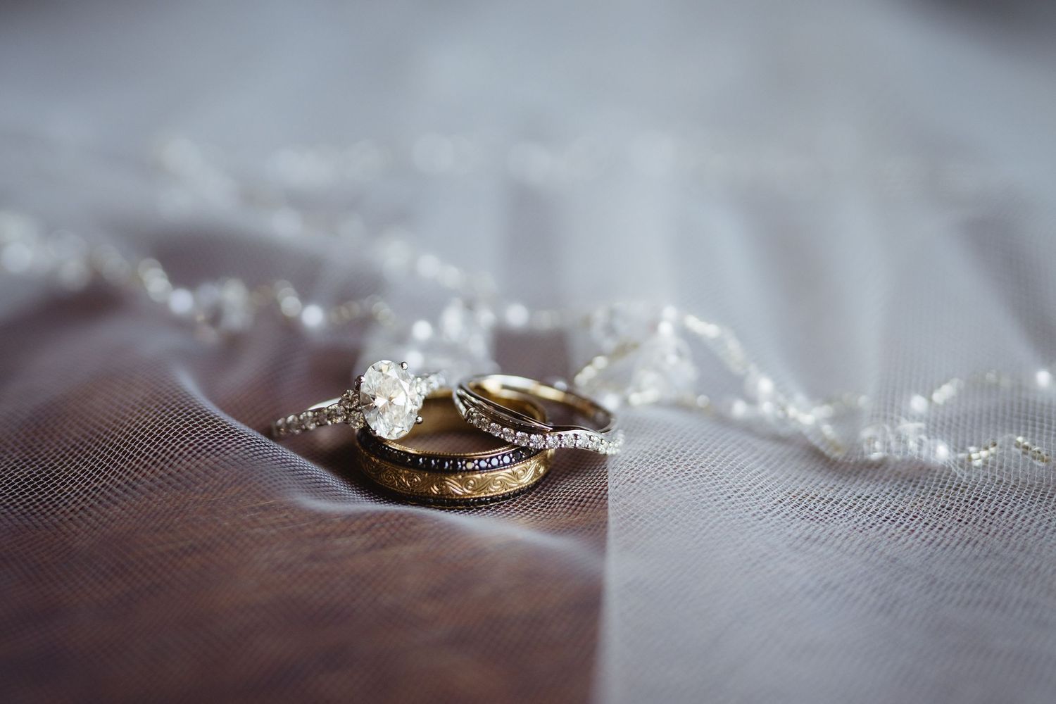 Two gold wedding rings resting on delicate white tulle fabric with soft bokeh effect in the background.