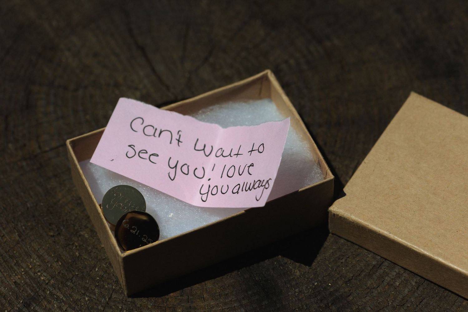 Handwritten love note inside a small box on dark wooden surface.