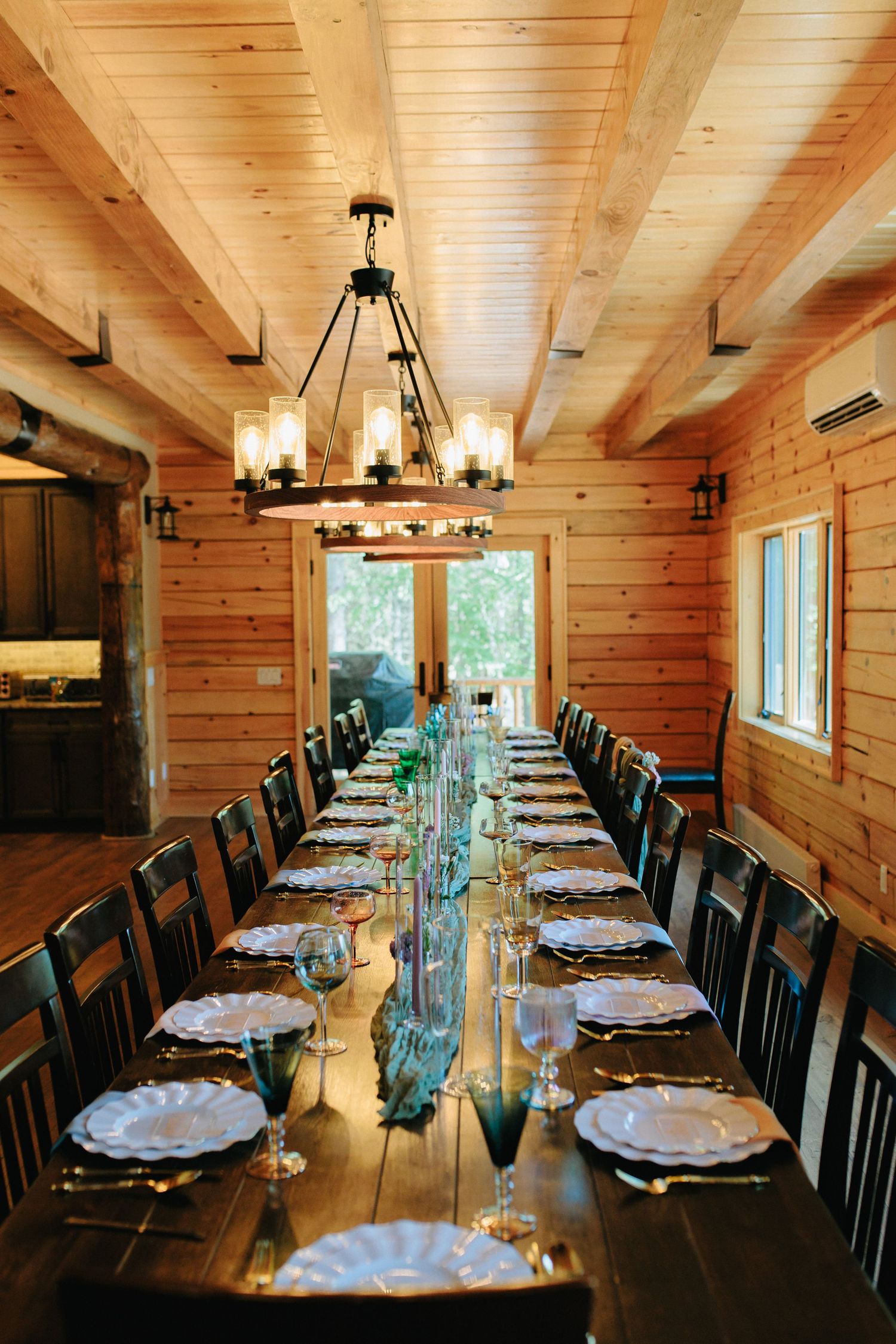 Rustic wooden dining room with elegant table settings and chandelier lighting.