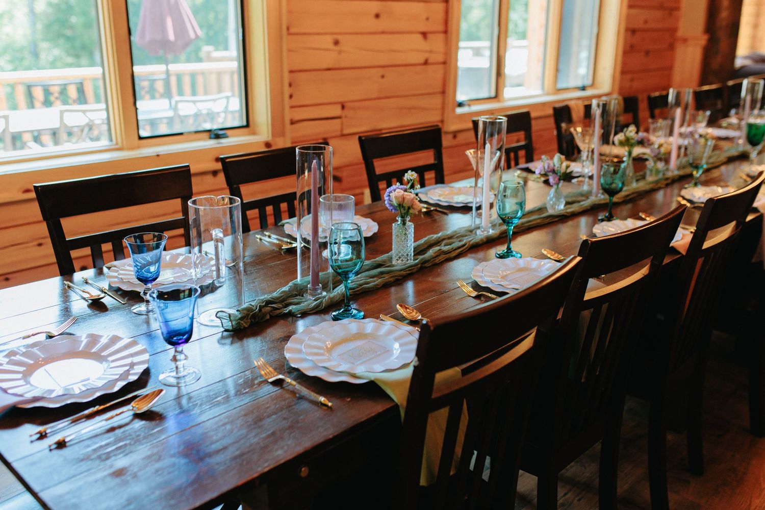 Long wooden dining table set for a rustic wedding reception with place settings and natural decor.