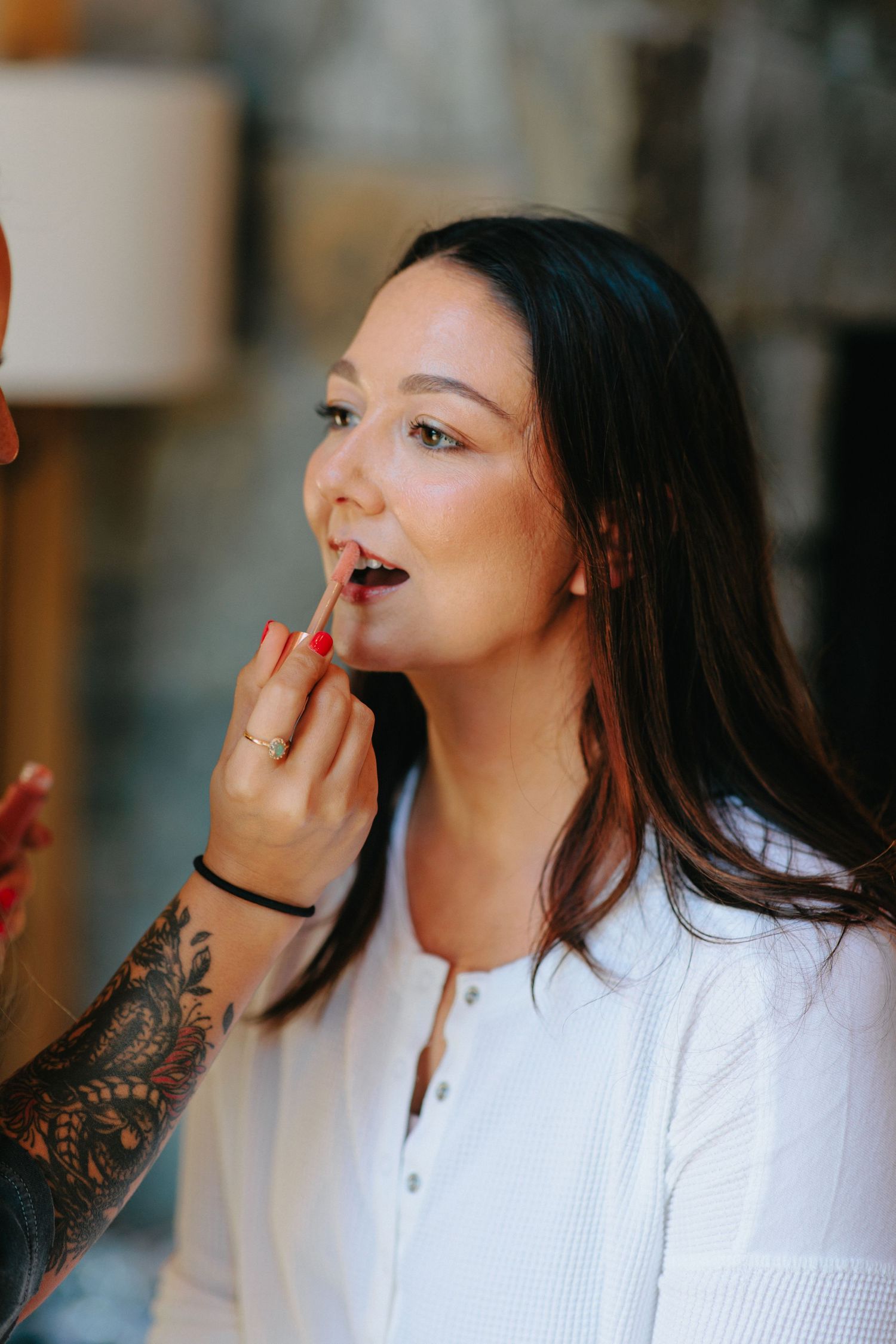 Makeup artist applying lipstick during bridal preparation.