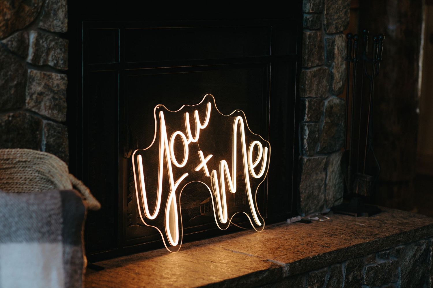 Love neon sign glowing against dark rustic wall at wedding venue.