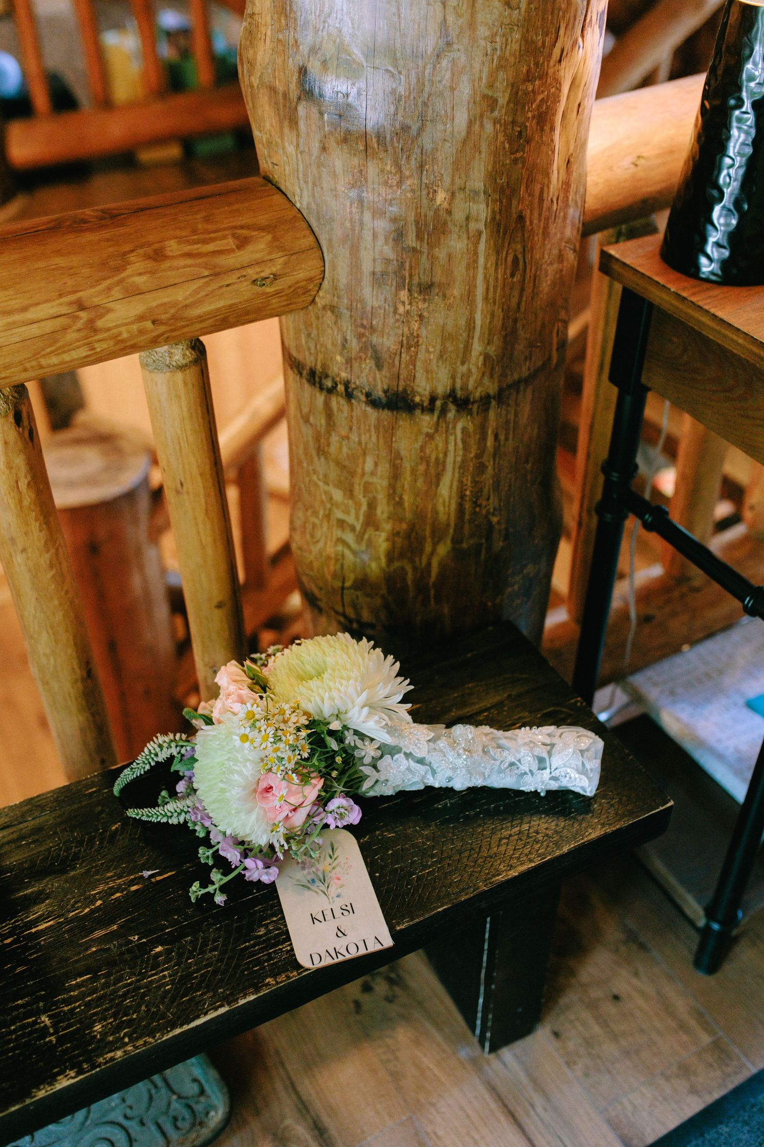 Delicate bridal bouquet with pink and white flowers resting on rustic wooden bench.