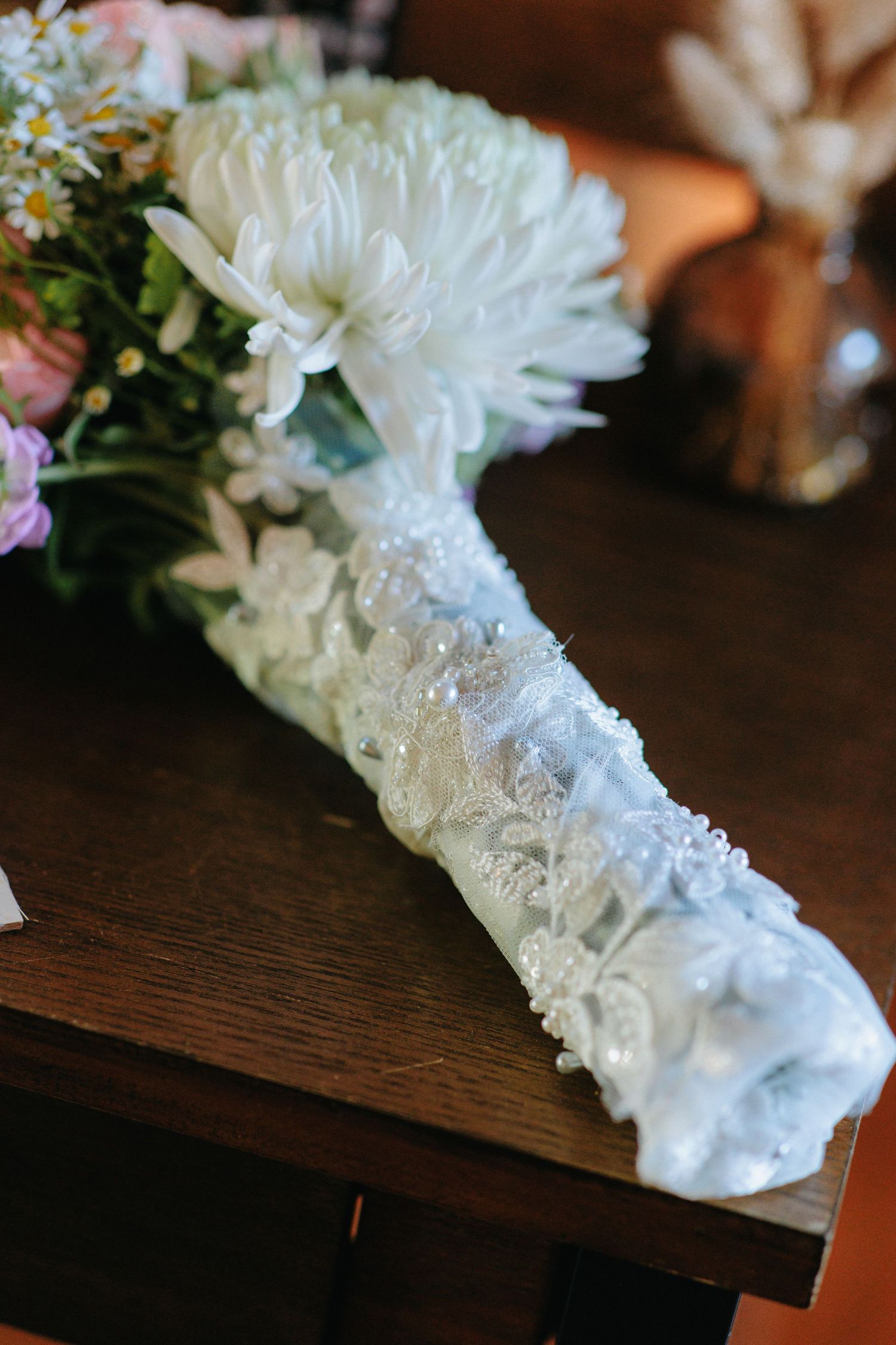 White lace garter with flowers displayed on dark wooden surface.