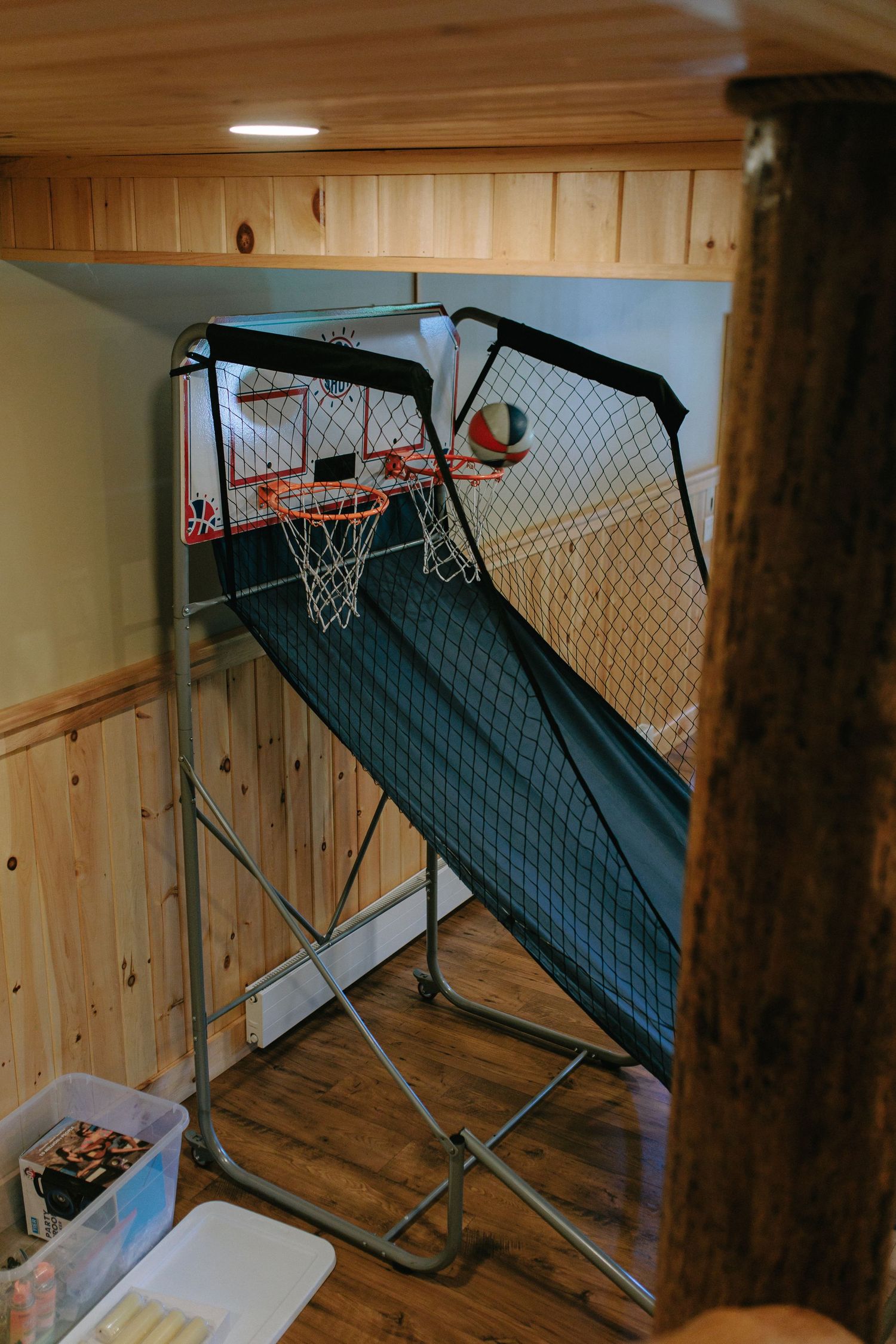 Indoor basketball arcade game setup in a wood-paneled room.