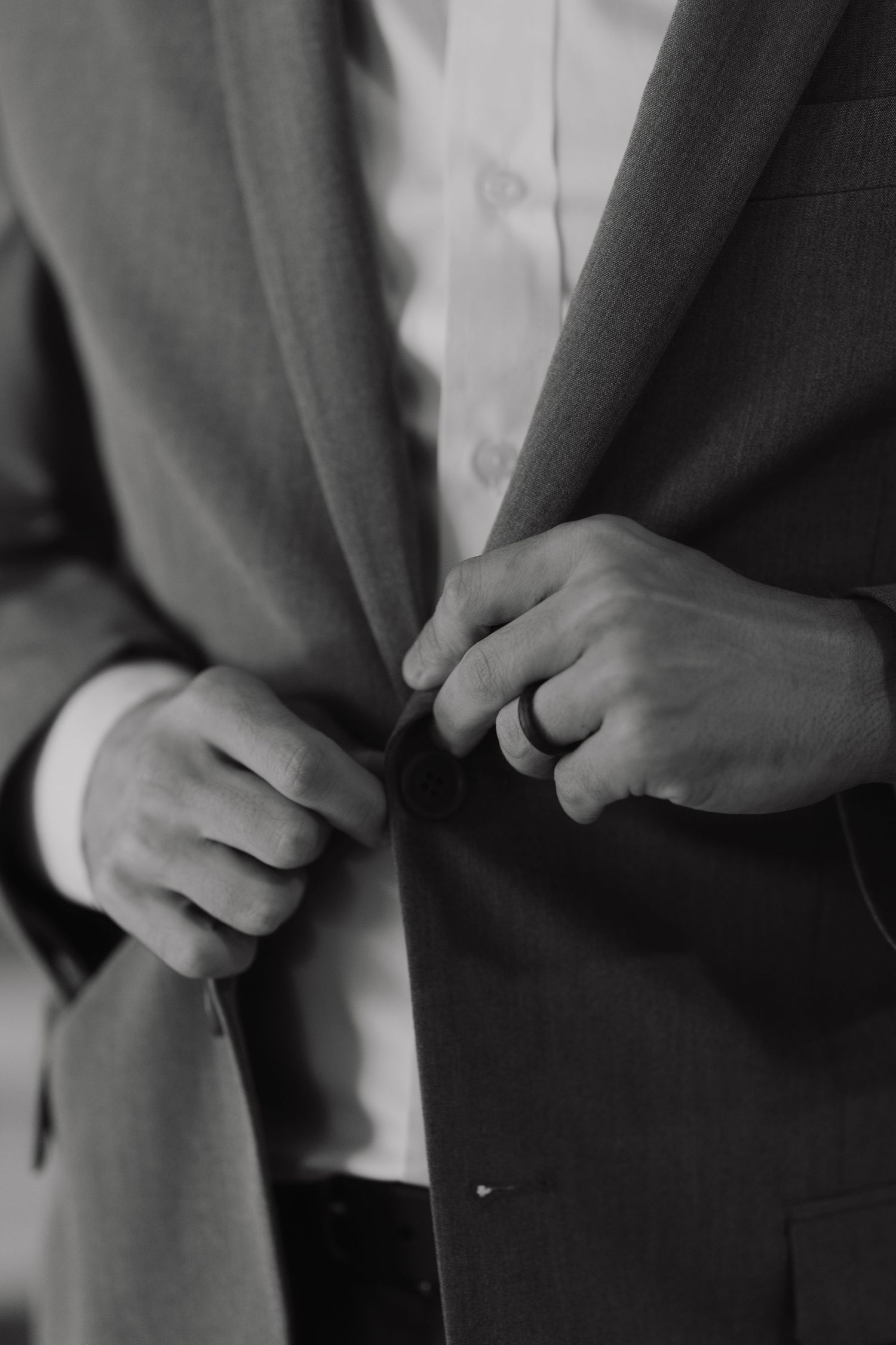 Close-up sequence showing hands buttoning up a formal dark suit jacket.