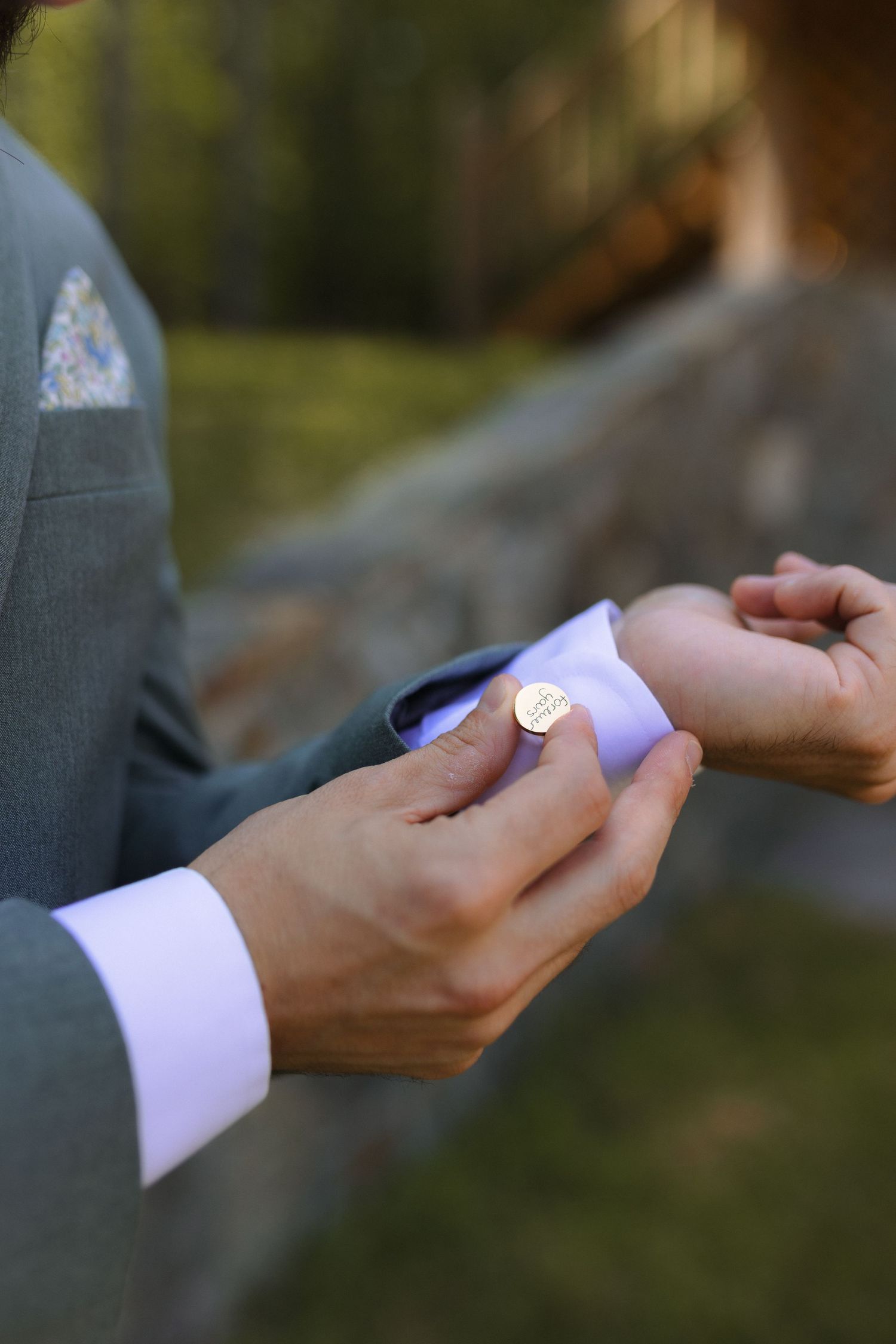 Close-up of hands exchanging rings during an outdoor wedding ceremony.