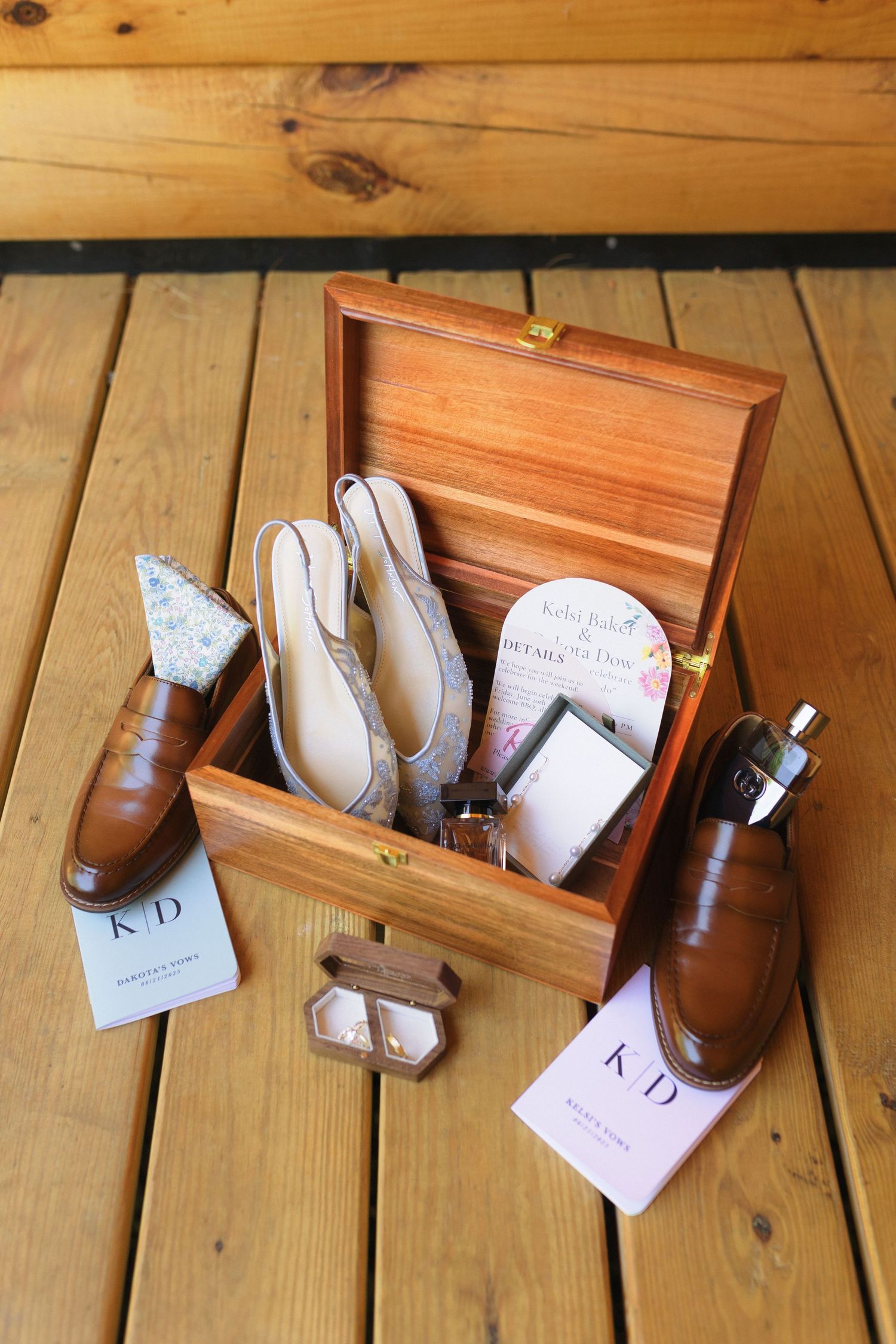 Brown leather dress shoes and accessories arranged with a wooden box on wooden deck.
