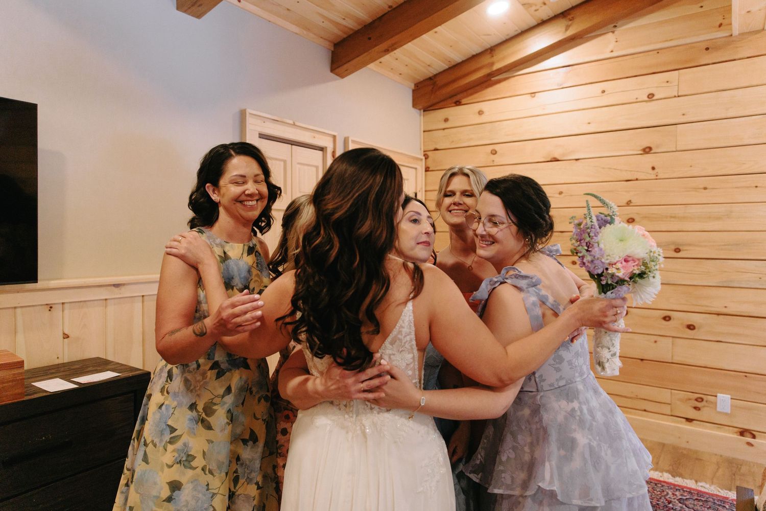 People embrace and celebrate during a joyful moment inside a rustic wooden cabin interior.