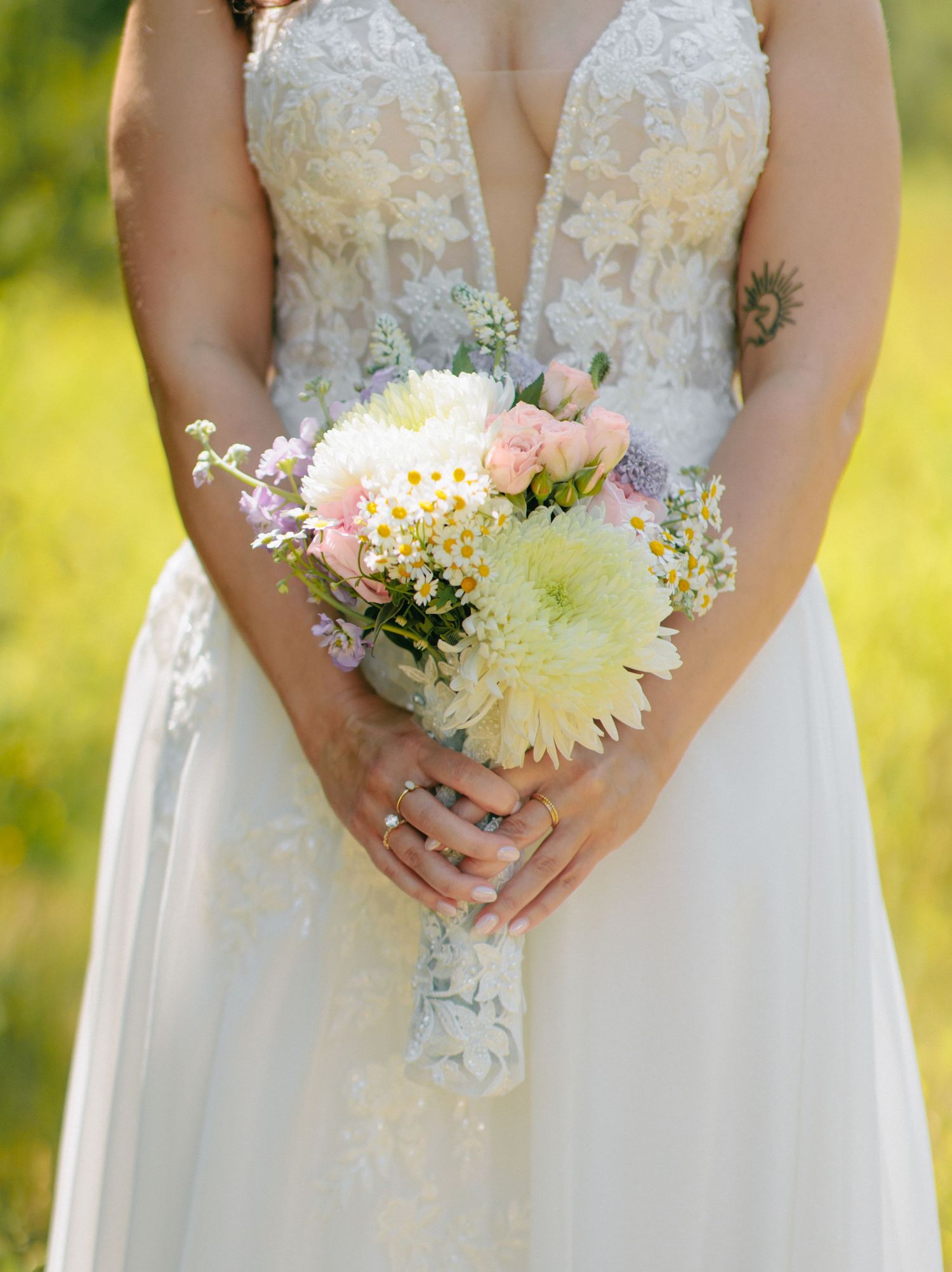 Close-up details of a white bridal bouquet featuring delicate dahlias and small wildflowers against a white wedding dress.