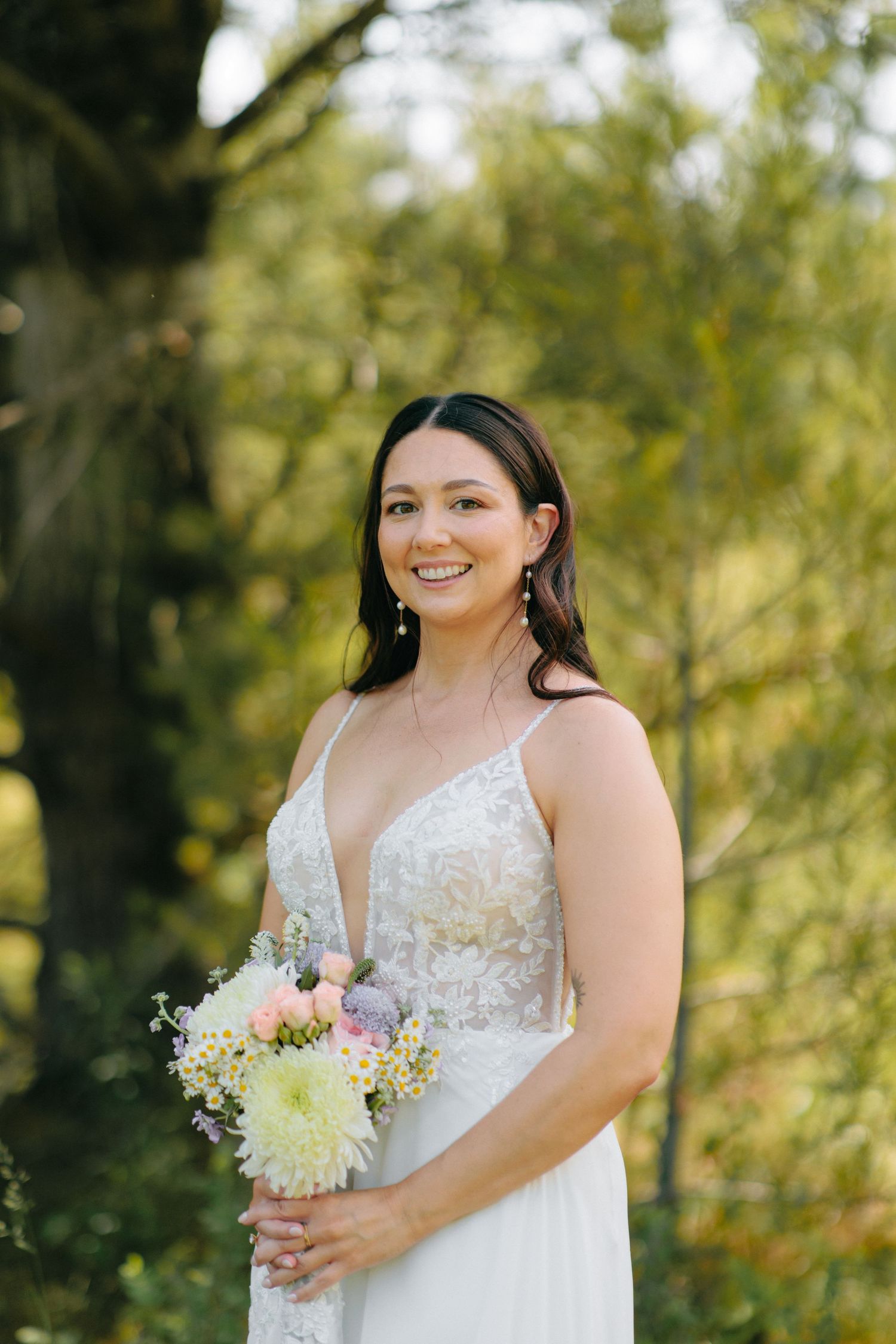 Close-up shots of a bride in a beautiful lace wedding dress holding a delicate bouquet outdoors.