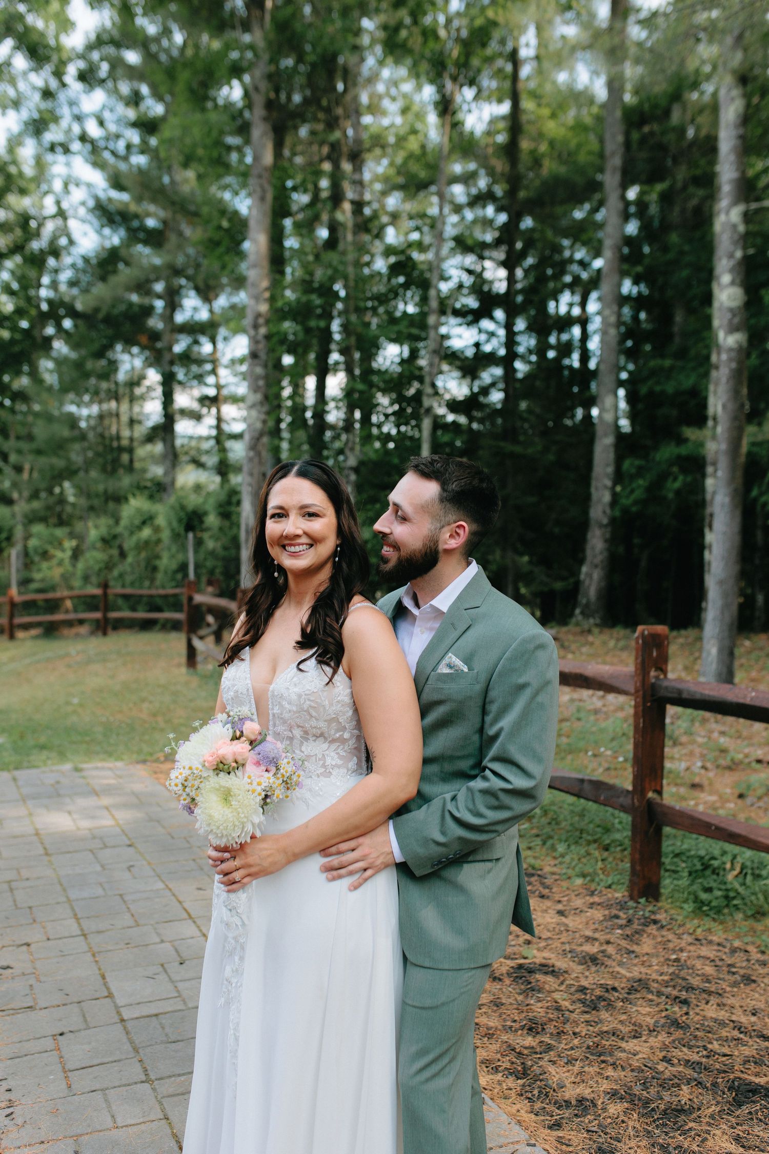 A couple shares loving moments on a stone pathway surrounded by pine trees.