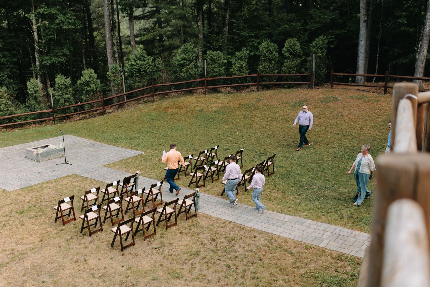 Wedding ceremony setup with wooden chairs arranged outdoors on a grassy hillside.