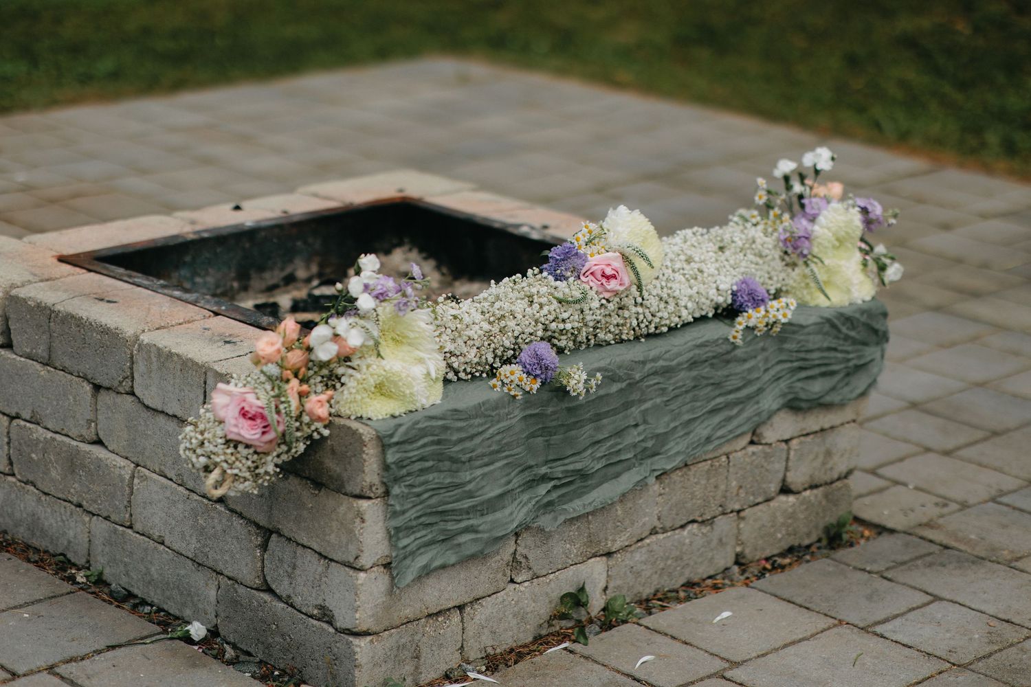 Stone planter boxes with floral arrangements decorating an outdoor patio space.