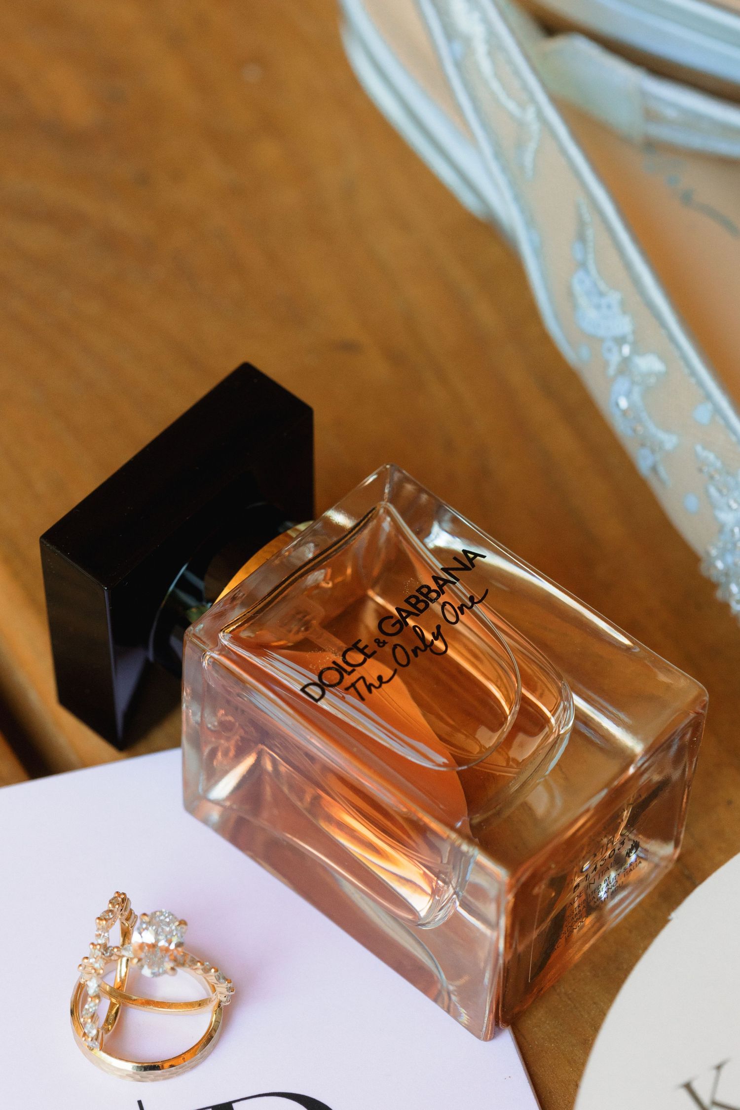 Perfume bottle and jewelry arranged on white surface for wedding detail shot.