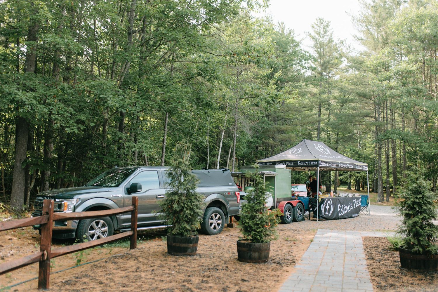 Cars parked along a wooded campground road surrounded by tall pine trees and natural forest scenery.