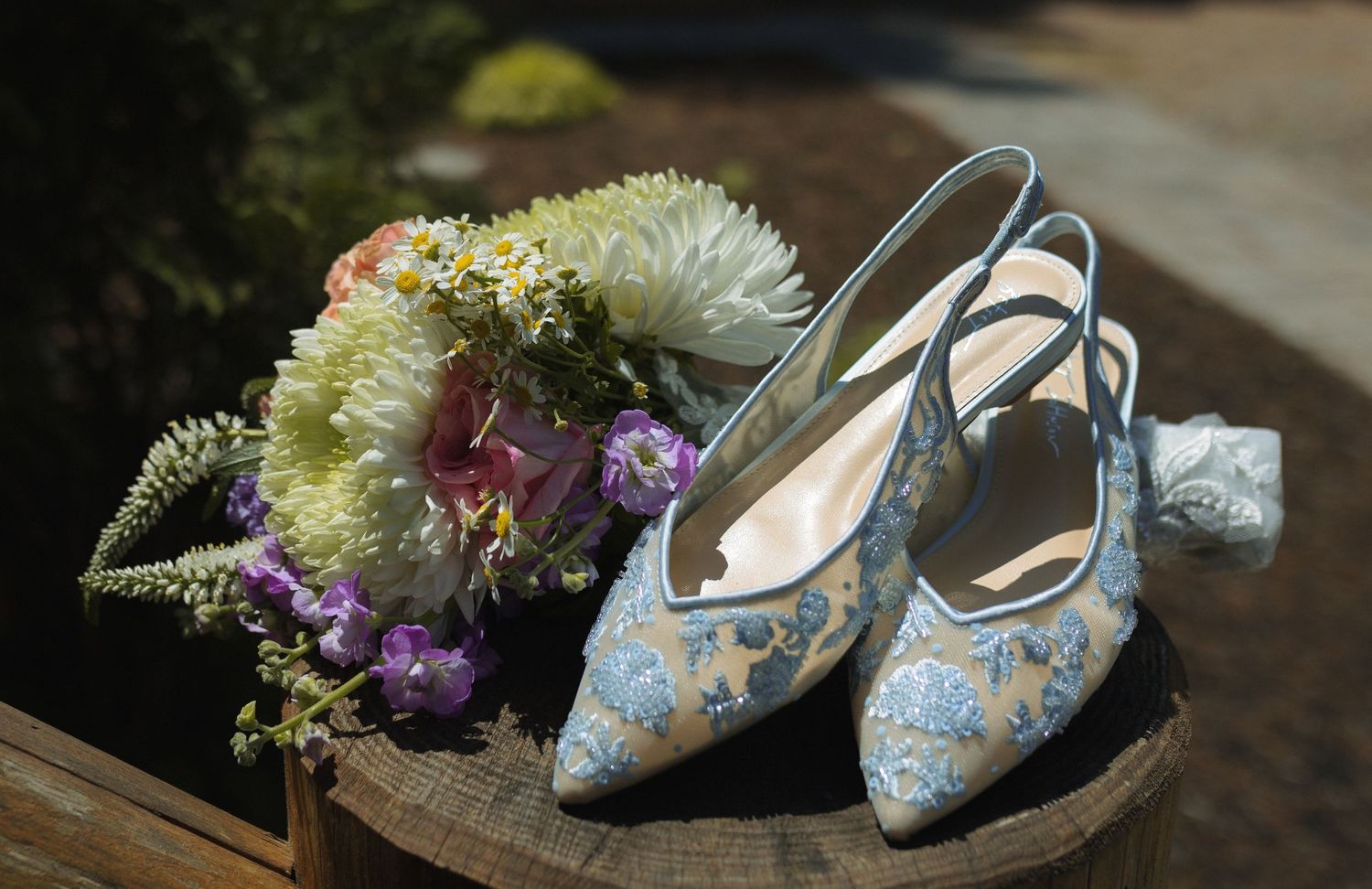 Delicate blue floral wedding shoes with floral bouquet arrangement.