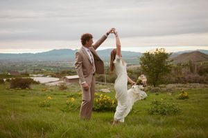 Couple celebrates with high five in scenic mountain landscape valley during golden sunset hour outdoors.