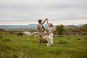 A couple dances together in a beautiful natural landscape with rolling hills and overcast skies during their outdoor wedding.