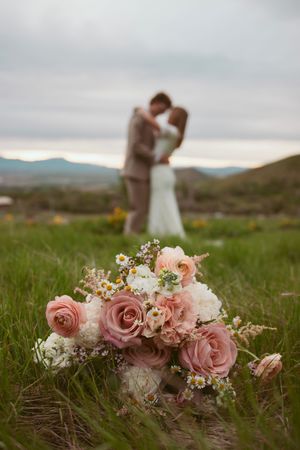 A romantic wedding photo sequence featuring a pink and white rose bouquet in the grass with a couple embracing in the background.