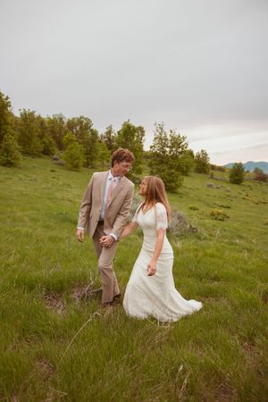 A couple shares a romantic moment on a green hillside during a spring wedding photoshoot.